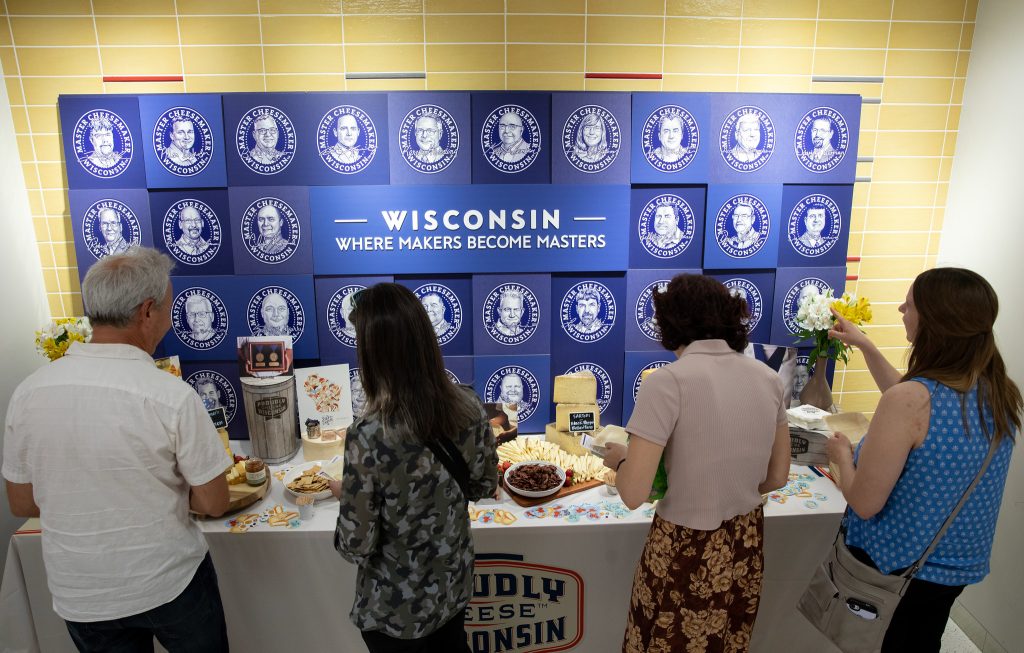 Four individuals shown at a table featuring products of Wisconsin Master Cheesemakers.