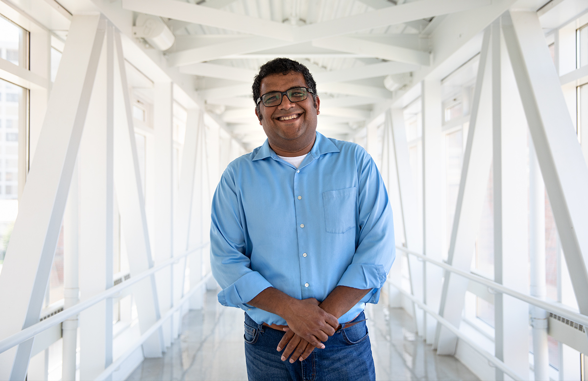 Vatsan Raman, associate professor of biochemistry, stands in a skywalk connected to the DeLuca Biochemistry Laboratories. Photo by Michael P. King