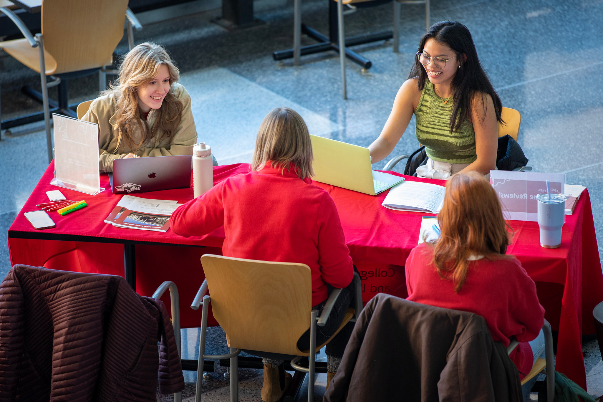 Three students sit at a table with an advisor